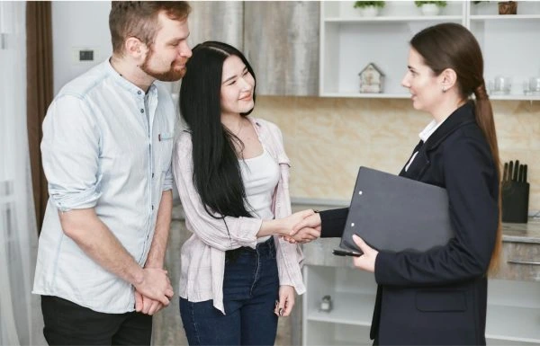 A photo of an insurance broker shaking hands with two clients.